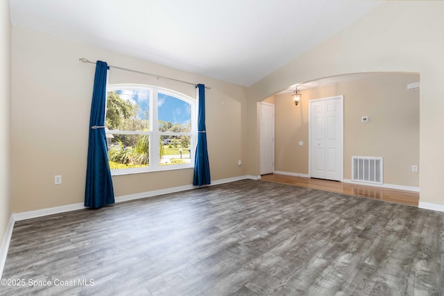 5230 Everett St, Cocoa, FL 32927 - unfurnished room featuring arched walkways, wood finished floors, baseboards, and vaulted ceiling