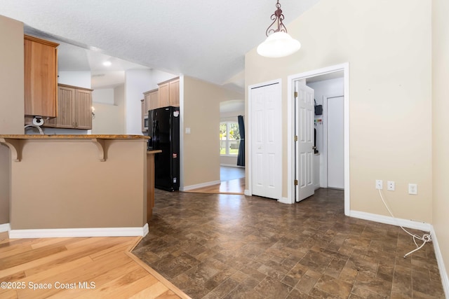 5230 Everett St, Cocoa, FL 32927 - kitchen with freestanding refrigerator, a breakfast bar area, a peninsula, baseboards, and vaulted ceiling