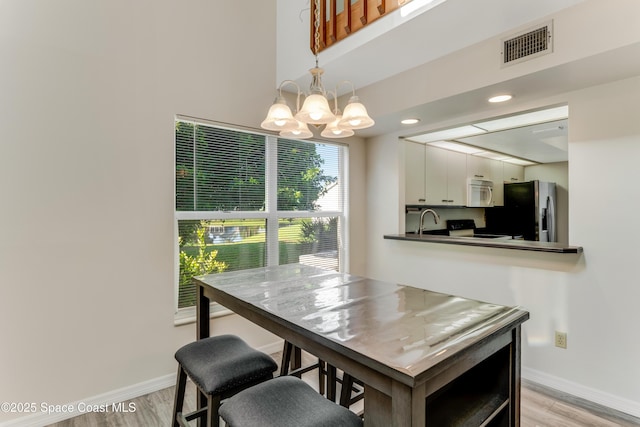 950 Vanessa Ct Unit F, Port Orange, FL 32127 - dining space with a chandelier, baseboards, and light wood finished floors