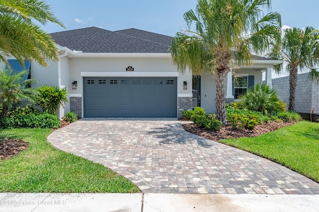 2679 Avalonia Dr, Melbourne, FL 32940 - view of front facade featuring decorative driveway, an attached garage, stucco siding, stone siding, and a front yard