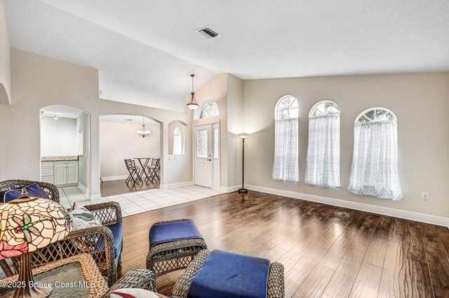 4040 Estancia Way, Melbourne, FL 32934 - living area featuring arched walkways, vaulted ceiling, wood finished floors, a chandelier, and baseboards