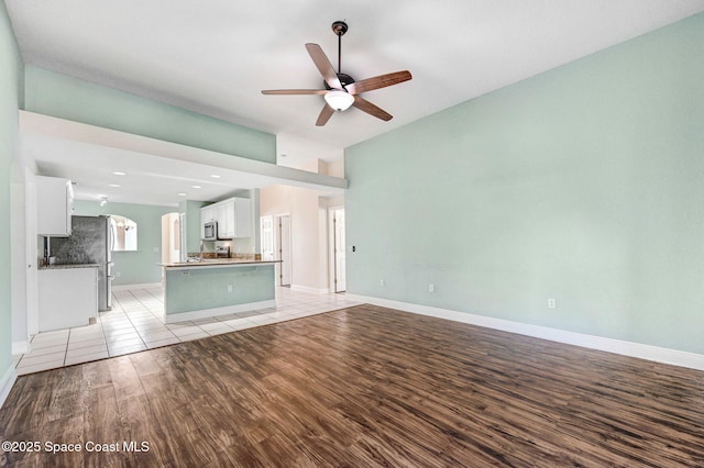 4040 Estancia Way, Melbourne, FL 32934 - unfurnished living room featuring ceiling fan, light wood-style flooring, arched walkways, and baseboards