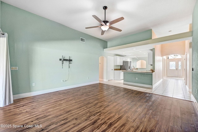 4040 Estancia Way, Melbourne, FL 32934 - unfurnished living room featuring arched walkways, light wood finished floors, ceiling fan, a sink, and baseboards