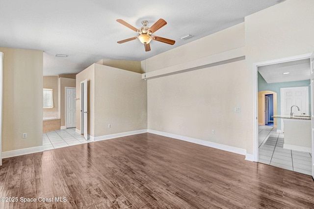 4040 Estancia Way, Melbourne, FL 32934 - unfurnished living room featuring ceiling fan, light wood-style floors, arched walkways, and baseboards