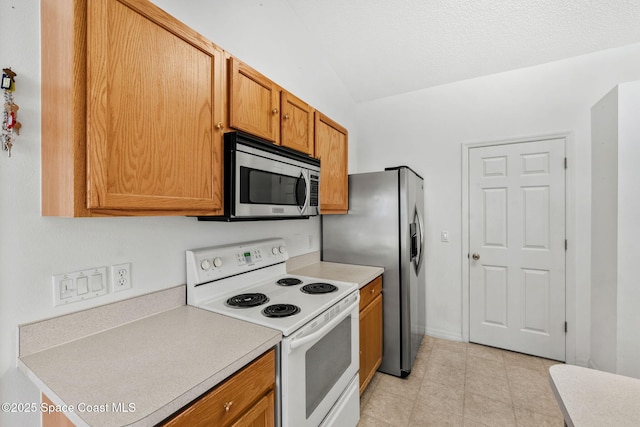 701 Agena Ave NW, Palm Bay, FL 32907 - kitchen featuring stainless steel appliances, vaulted ceiling, light countertops, brown cabinetry, and light tile patterned floors