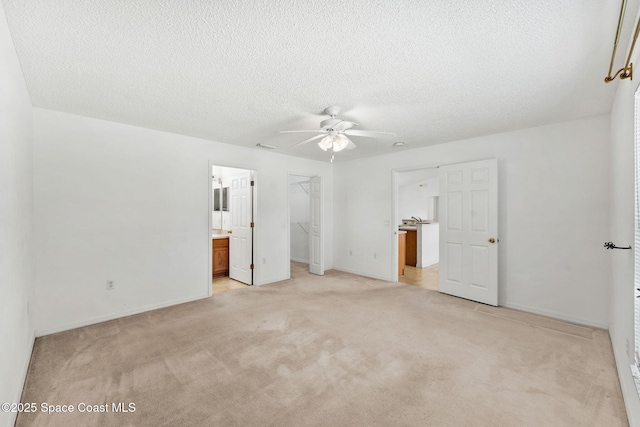 701 Agena Ave NW, Palm Bay, FL 32907 - unfurnished bedroom featuring a spacious closet, light colored carpet, ensuite bath, a textured ceiling, and a closet