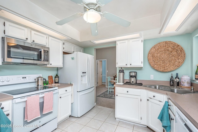 kitchen with white appliances, a ceiling fan, a sink, light tile patterned flooring, and white cabinetry