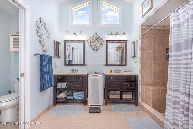 bathroom with tile patterned floors, a tile shower, toilet, and vanity