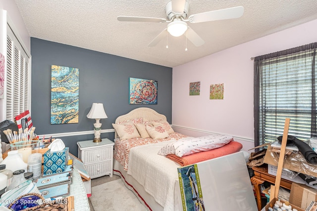 bedroom featuring a textured ceiling, carpet floors, a ceiling fan, and a closet