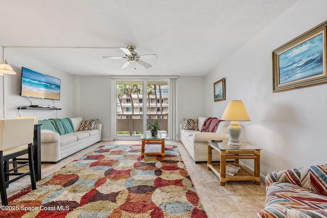 living area with light tile patterned flooring, ceiling fan, and baseboards
