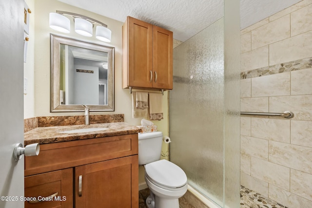 full bathroom with a shower stall, toilet, vanity, and a textured ceiling
