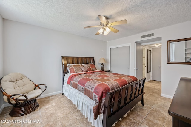 bedroom with light tile patterned flooring, a textured ceiling, a closet, a ceiling fan, and baseboards