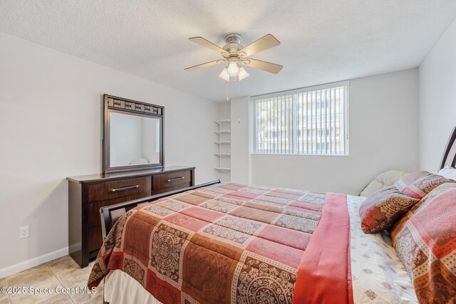 bedroom with a ceiling fan, light tile patterned floors, a textured ceiling, and baseboards