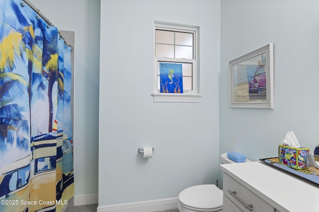 full bath featuring toilet, baseboards, vanity, and curtained shower