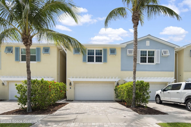 view of property featuring a garage, decorative driveway, and stucco siding