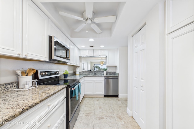 kitchen featuring appliances with stainless steel finishes, white cabinets, ceiling fan, a sink, and light stone counters