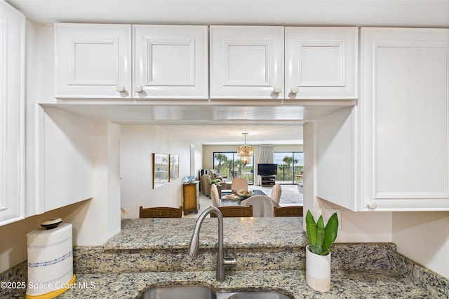kitchen featuring a sink, white cabinets, and light stone counters