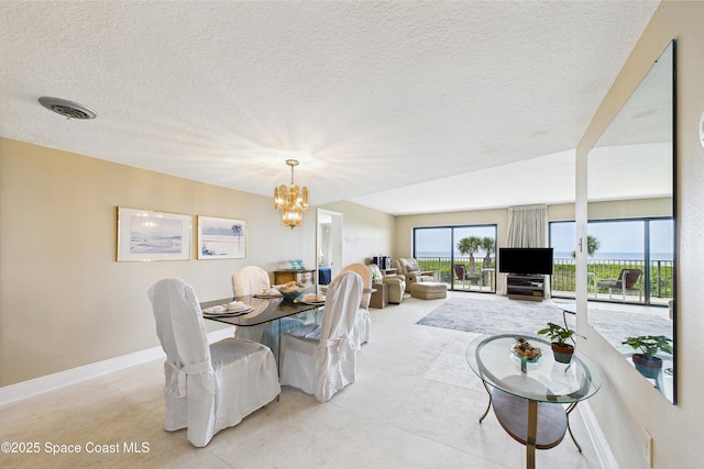 dining room with a chandelier, a textured ceiling, light tile patterned floors, and baseboards