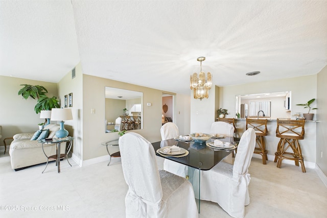 dining area featuring a chandelier, baseboards, and a textured ceiling