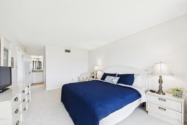 bedroom featuring light carpet and ensuite bathroom