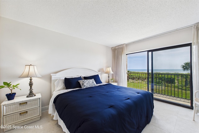 bedroom featuring access to exterior, a textured ceiling, and a water view