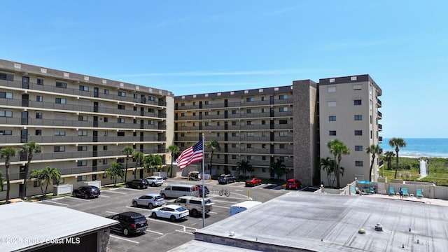 view of apartment building / complex featuring uncovered parking and a water view