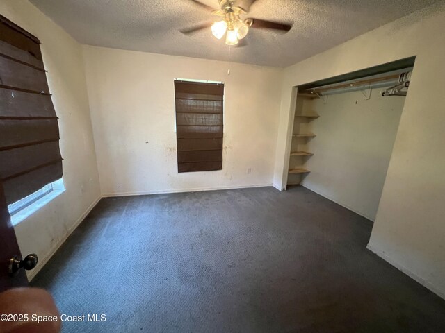 unfurnished bedroom with a textured ceiling, dark colored carpet, and a ceiling fan