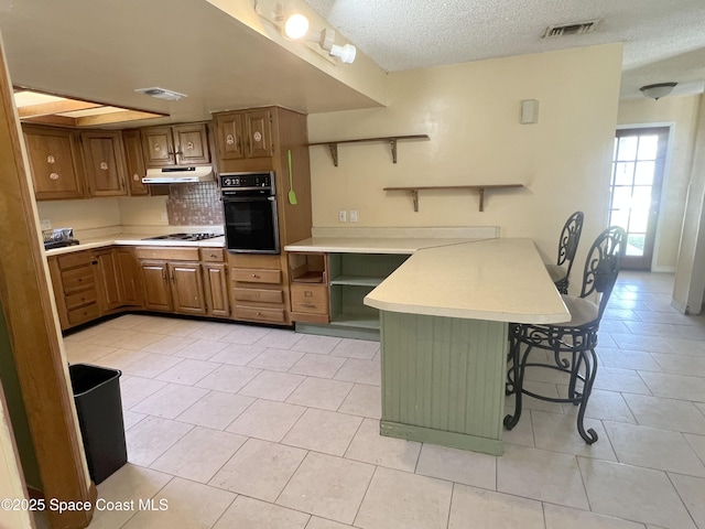 kitchen featuring oven, under cabinet range hood, a peninsula, open shelves, and a textured ceiling