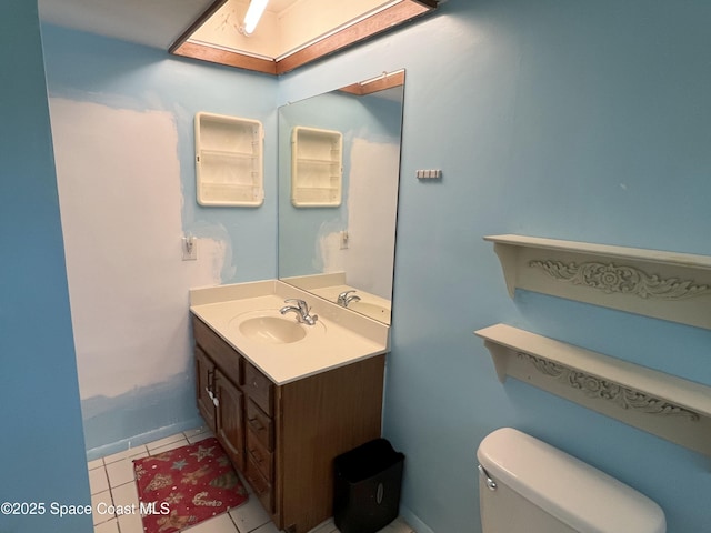 half bathroom featuring vanity, toilet, tile patterned flooring, and baseboards