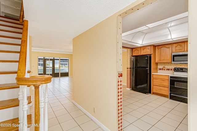 411 Dove Ln Unit 6-11, Satellite Beach, FL 32937 - kitchen featuring electric stove, freestanding refrigerator, stainless steel microwave, light tile patterned flooring, and light countertops