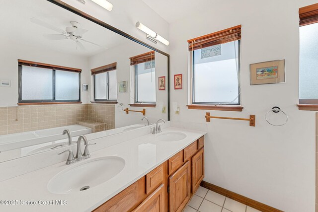 1875 Halifax Ave, Melbourne, FL 32935 - bathroom featuring tile patterned flooring, double vanity, a ceiling fan, a bath, and baseboards