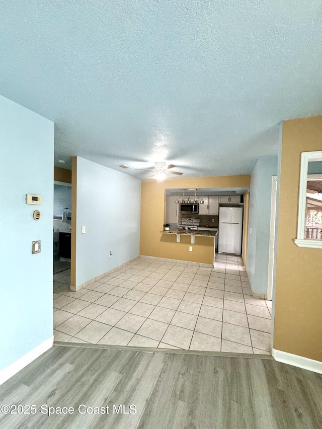 624 Ridge Club Dr Unit 86, Melbourne, FL 32934 - unfurnished living room with ceiling fan, a textured ceiling, light wood-style flooring, and baseboards