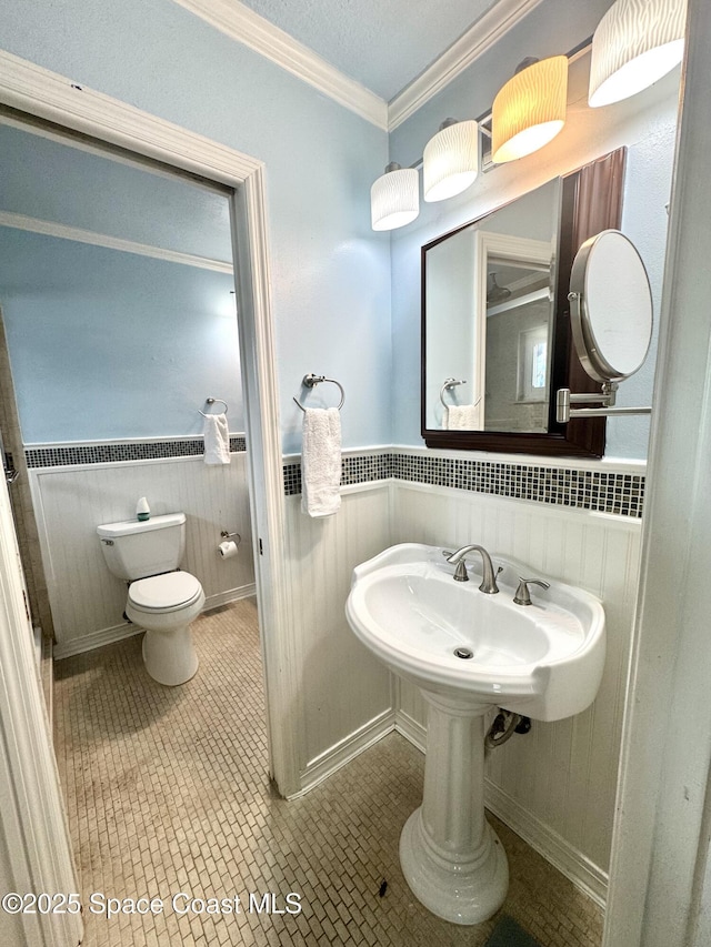 624 Ridge Club Dr Unit 86, Melbourne, FL 32934 - bathroom featuring toilet, crown molding, wainscoting, and tile patterned flooring