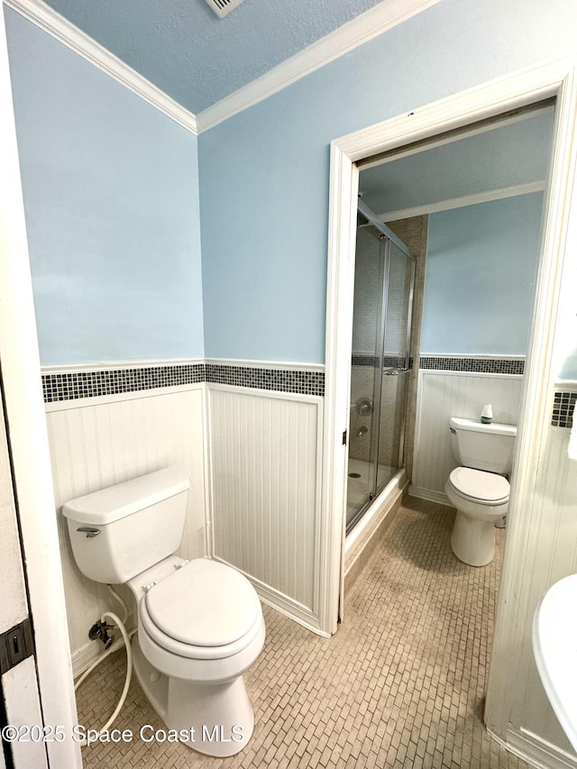624 Ridge Club Dr Unit 86, Melbourne, FL 32934 - bathroom featuring toilet, a shower stall, tile patterned flooring, a wainscoted wall, and crown molding