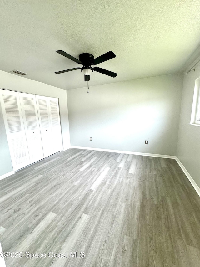 624 Ridge Club Dr Unit 86, Melbourne, FL 32934 - unfurnished bedroom with wood finished floors, a textured ceiling, baseboards, a closet, and ceiling fan