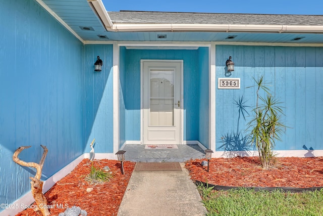 view of exterior entry with a shingled roof