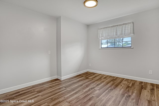 spare room featuring baseboards and wood finished floors