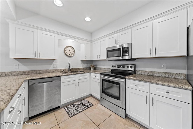 kitchen featuring stainless steel appliances, a sink, white cabinets, light tile patterned floors, and recessed lighting