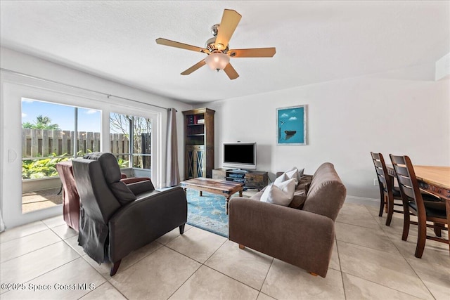 living area with ceiling fan, light tile patterned floors, and baseboards