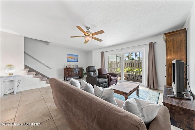 living room with ceiling fan, stairway, light tile patterned floors, and baseboards
