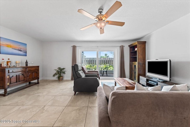 living area with ceiling fan, light tile patterned floors, baseboards, and a textured ceiling