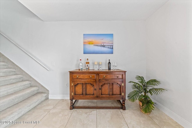 interior space with a dry bar, tile patterned flooring, and baseboards