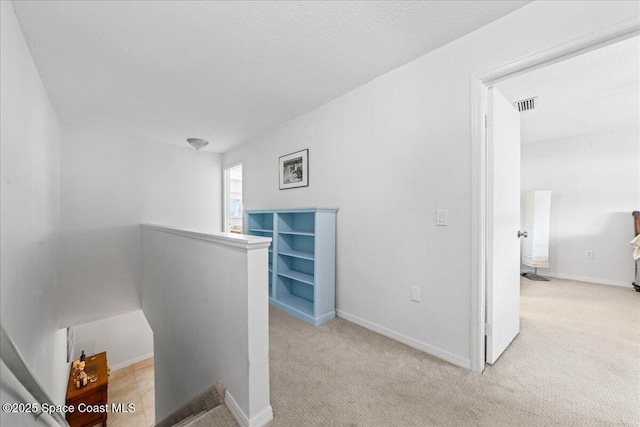 hallway featuring an upstairs landing, carpet flooring, and baseboards