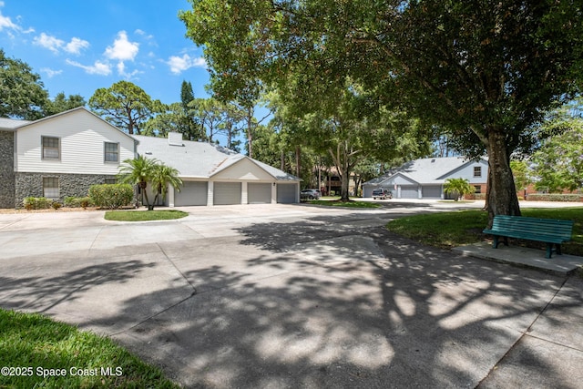 9020 Brighton Ct Unit 4-H, West Melbourne, FL 32904 - view of property exterior with stone siding, a chimney, driveway, and a garage