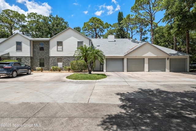 9020 Brighton Ct Unit 4-H, West Melbourne, FL 32904 - view of property featuring concrete driveway, a garage, a chimney, and stone siding
