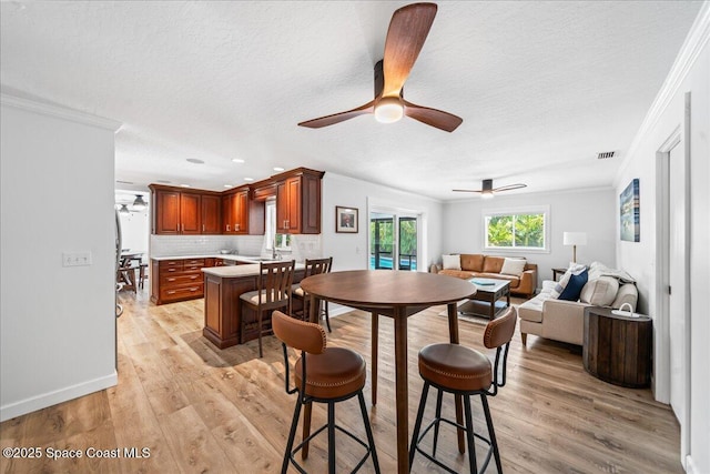 515 Hibiscus Trl, Melbourne Beach, FL 32951 - dining area with ornamental molding, a textured ceiling, light wood-style flooring, a ceiling fan, and baseboards