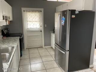 kitchen featuring freestanding refrigerator, white cabinetry, range with electric cooktop, and light tile patterned floors