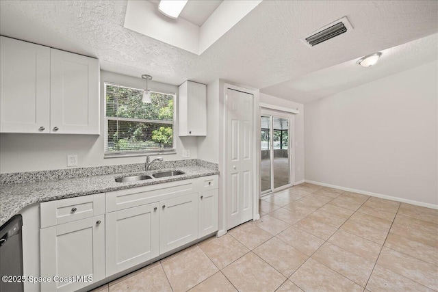 kitchen with a sink, a textured ceiling, black dishwasher, white cabinets, and light tile patterned floors
