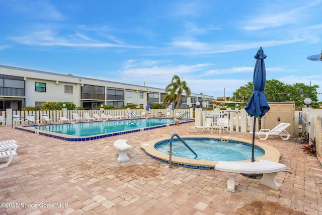community pool featuring fence, a hot tub, and a patio