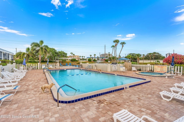 community pool featuring a community hot tub, a patio area, and fence